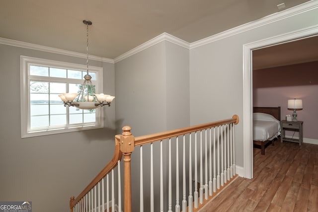 hall featuring crown molding, wood-type flooring, and a chandelier