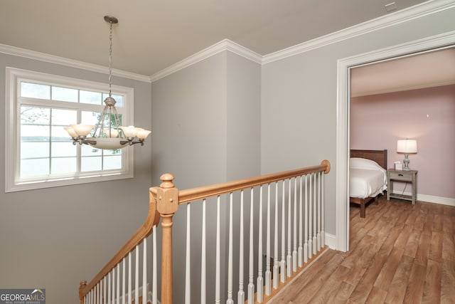 hallway featuring ornamental molding, hardwood / wood-style floors, and a chandelier