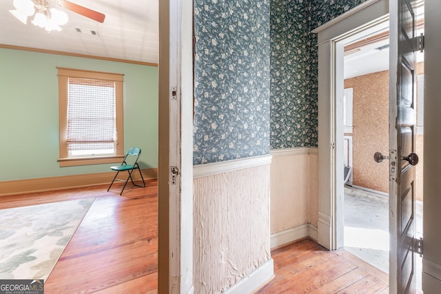 corridor with ornamental molding and light wood-type flooring