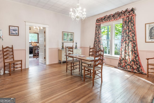 dining room featuring hardwood / wood-style flooring, a wealth of natural light, crown molding, and an inviting chandelier