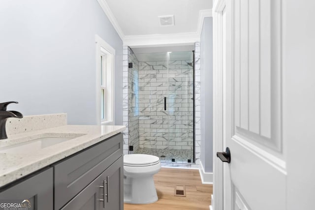 bathroom featuring a shower with door, toilet, wood-type flooring, crown molding, and vanity