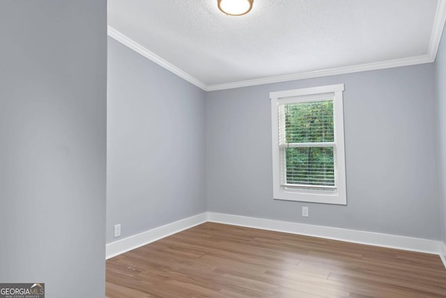 empty room featuring crown molding, a textured ceiling, and wood-type flooring