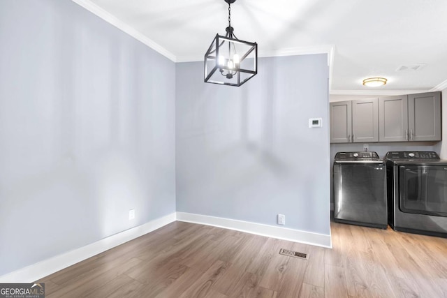 interior space with ornamental molding, washing machine and dryer, and light wood-type flooring