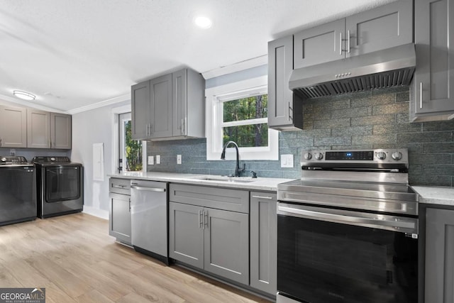 kitchen with appliances with stainless steel finishes, plenty of natural light, sink, and washing machine and dryer