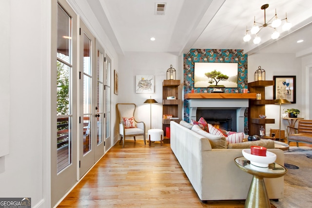 living room featuring light wood-type flooring, a chandelier, and french doors