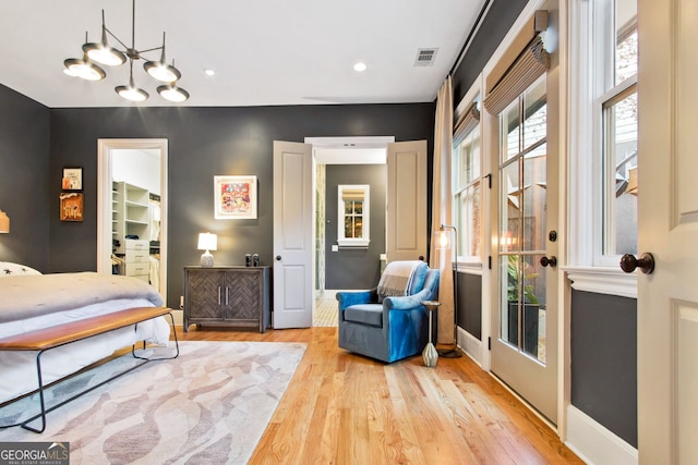 bedroom featuring an inviting chandelier, a spacious closet, and light hardwood / wood-style flooring