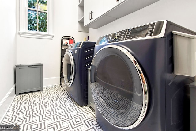 clothes washing area with washing machine and dryer and cabinets