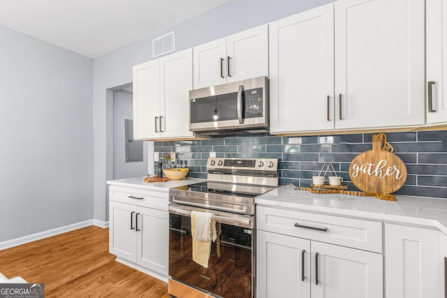 kitchen with light wood finished floors, visible vents, backsplash, light countertops, and appliances with stainless steel finishes