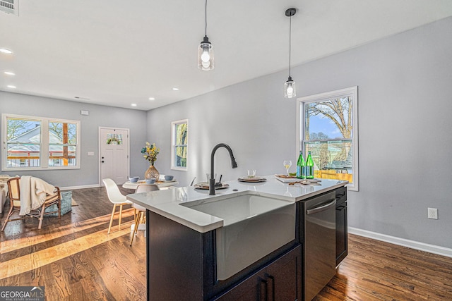 kitchen with baseboards, dark wood finished floors, light countertops, hanging light fixtures, and stainless steel dishwasher