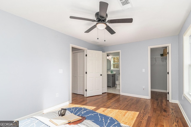 unfurnished bedroom with wood finished floors, visible vents, baseboards, ensuite bath, and a spacious closet