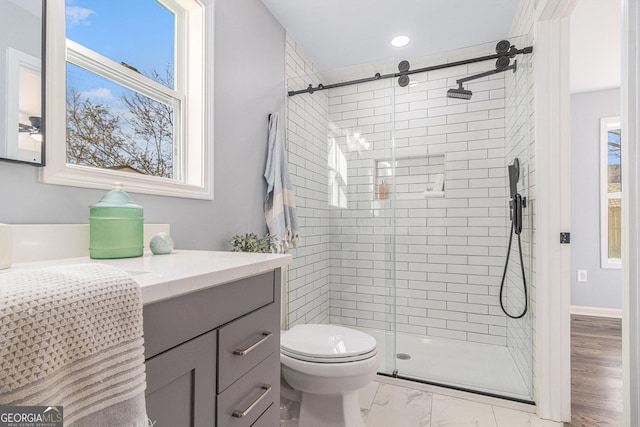 bathroom featuring a shower stall, baseboards, toilet, marble finish floor, and vanity