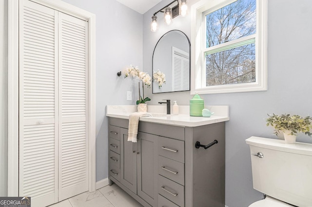 bathroom with a closet, marble finish floor, vanity, and toilet