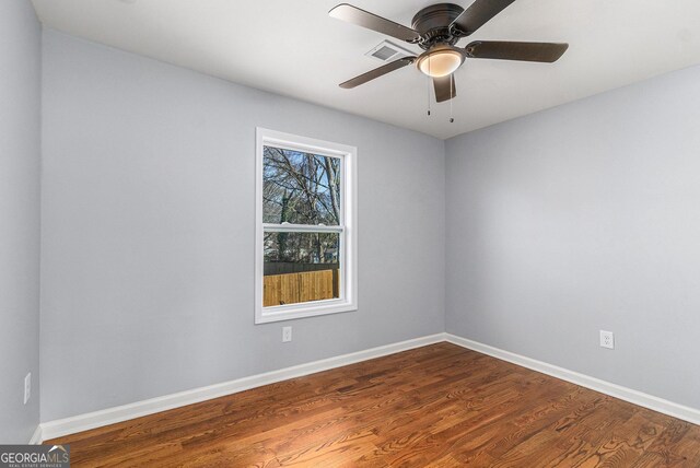 empty room featuring ceiling fan, baseboards, and dark wood-style flooring