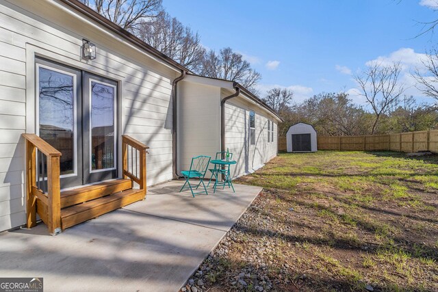 view of yard featuring an outbuilding, a patio area, a storage shed, and fence