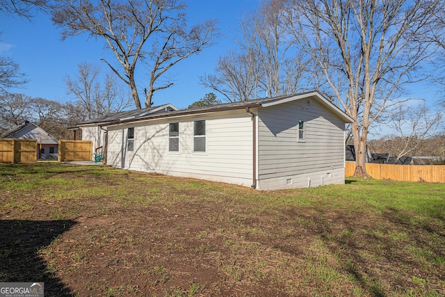 view of side of home with crawl space, a yard, and fence