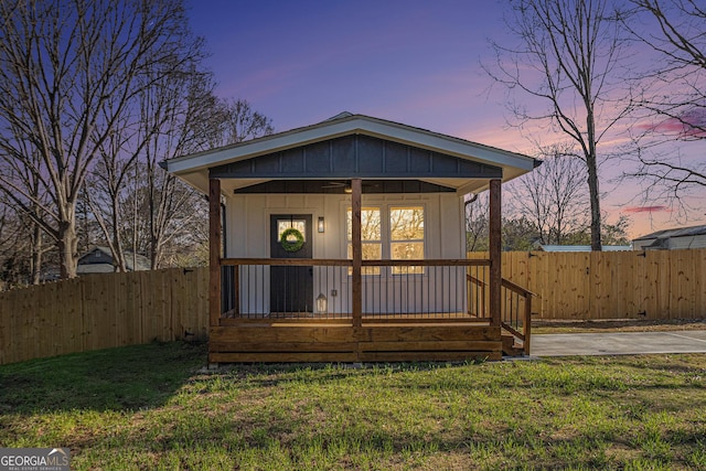 exterior space with a porch, a yard, fence, and board and batten siding