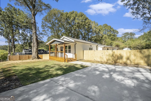 view of front of house featuring a deck, a front lawn, fence private yard, and a patio