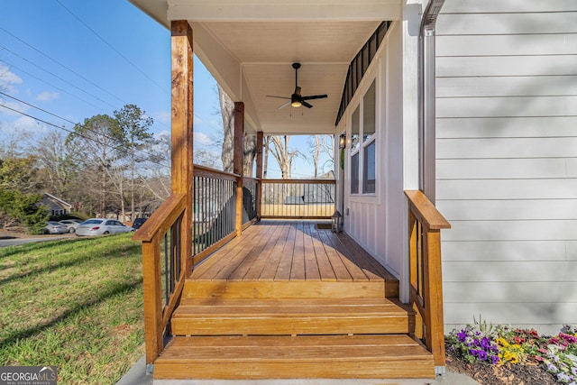 wooden deck with a lawn and a ceiling fan