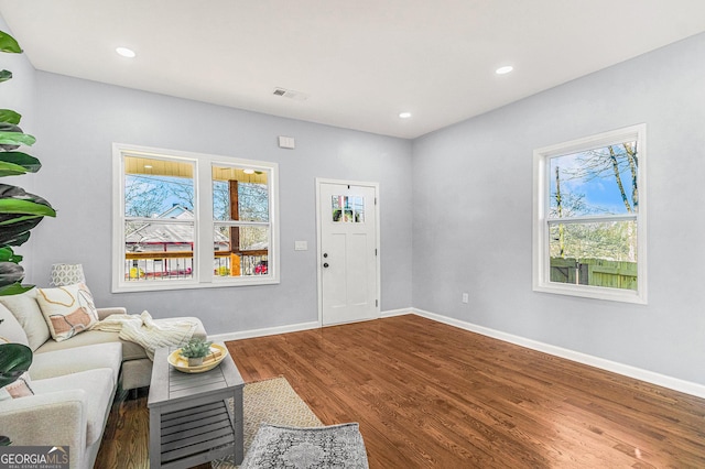 living area with recessed lighting, visible vents, baseboards, and wood finished floors