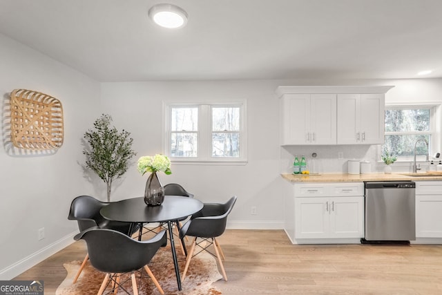 kitchen featuring dishwasher, light hardwood / wood-style floors, plenty of natural light, and white cabinetry