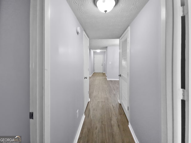 hallway featuring hardwood / wood-style floors and a textured ceiling