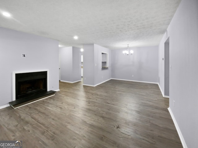 unfurnished living room with a chandelier, a textured ceiling, and dark hardwood / wood-style flooring