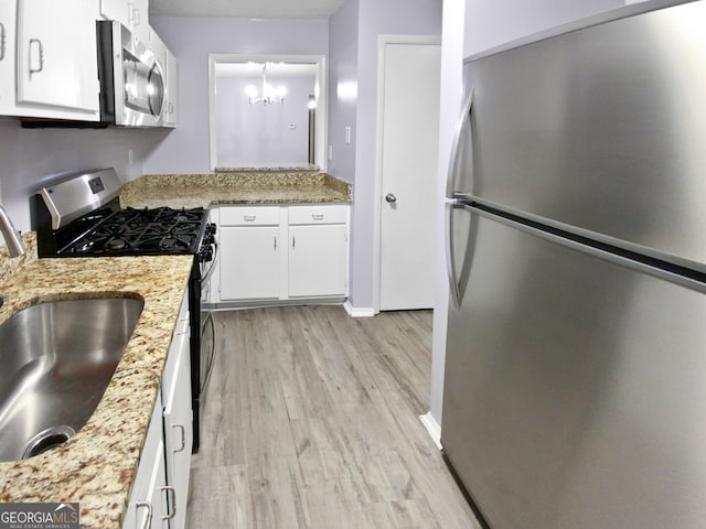 kitchen with light hardwood / wood-style flooring, stainless steel appliances, light stone countertops, a chandelier, and white cabinets