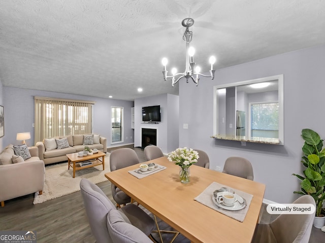 dining space featuring a textured ceiling, wood-type flooring, and an inviting chandelier