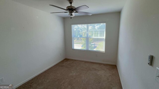 spare room with ceiling fan and light colored carpet