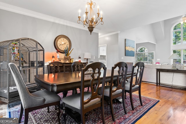 dining area featuring lofted ceiling, crown molding, a notable chandelier, and hardwood / wood-style flooring