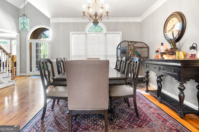 dining space featuring hardwood / wood-style floors, crown molding, an inviting chandelier, and plenty of natural light