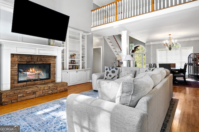 living room featuring hardwood / wood-style flooring, decorative columns, a high ceiling, a fireplace, and crown molding