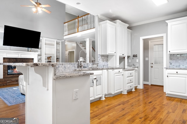 kitchen with white cabinets, tasteful backsplash, a kitchen bar, ornamental molding, and light hardwood / wood-style floors