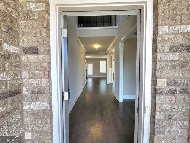 unfurnished living room with a fireplace with raised hearth, dark wood-style flooring, visible vents, and baseboards