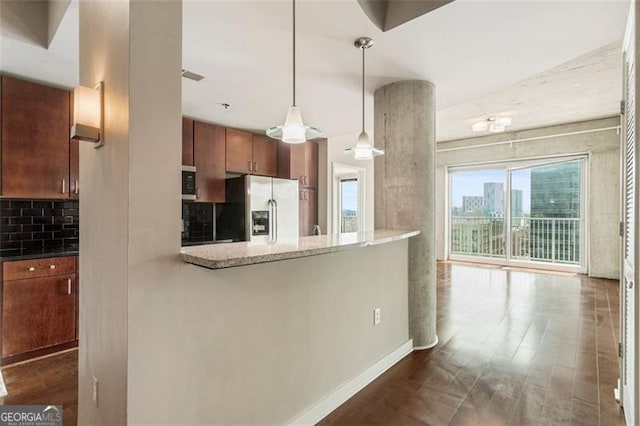 kitchen featuring dark wood-type flooring, hanging light fixtures, stainless steel appliances, light stone countertops, and tasteful backsplash