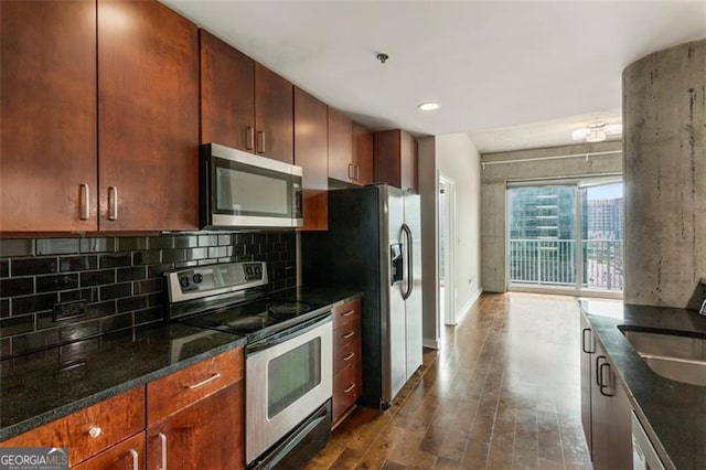 kitchen featuring sink, backsplash, stainless steel appliances, dark stone counters, and dark hardwood / wood-style floors