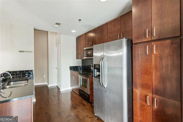 kitchen featuring decorative backsplash, stainless steel appliances, dark stone countertops, sink, and dark hardwood / wood-style flooring