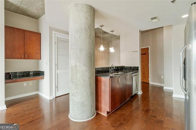 kitchen featuring dark wood-type flooring, appliances with stainless steel finishes, sink, and pendant lighting