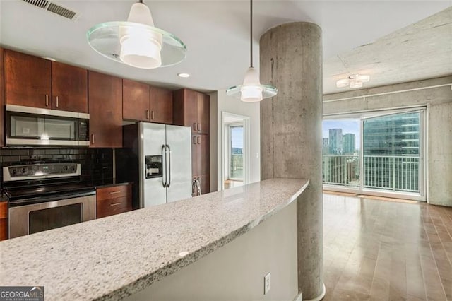 kitchen featuring light stone countertops, appliances with stainless steel finishes, decorative light fixtures, and light hardwood / wood-style floors