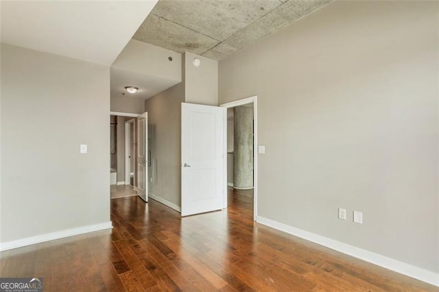 spare room featuring dark hardwood / wood-style floors and a high ceiling