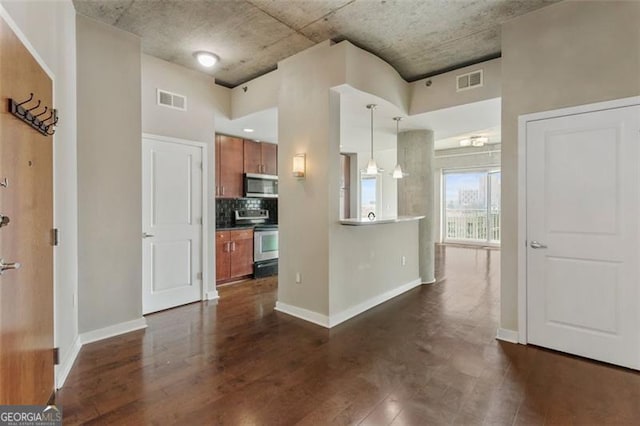 kitchen featuring stainless steel appliances, decorative backsplash, decorative light fixtures, and dark hardwood / wood-style flooring