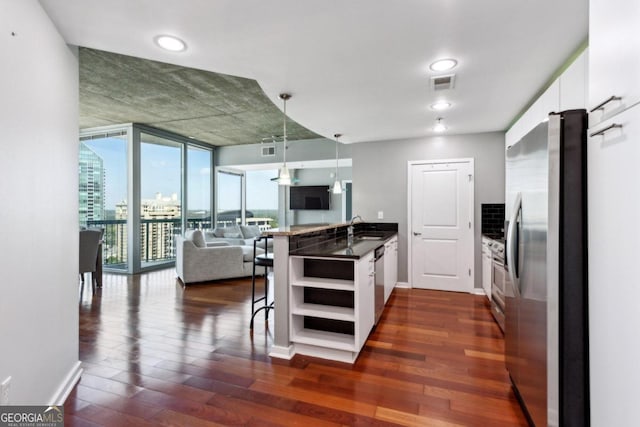 kitchen featuring white cabinetry, appliances with stainless steel finishes, dark hardwood / wood-style flooring, and a breakfast bar area