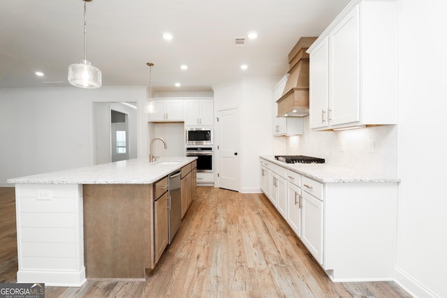 kitchen with white cabinets, visible vents, premium range hood, and appliances with stainless steel finishes