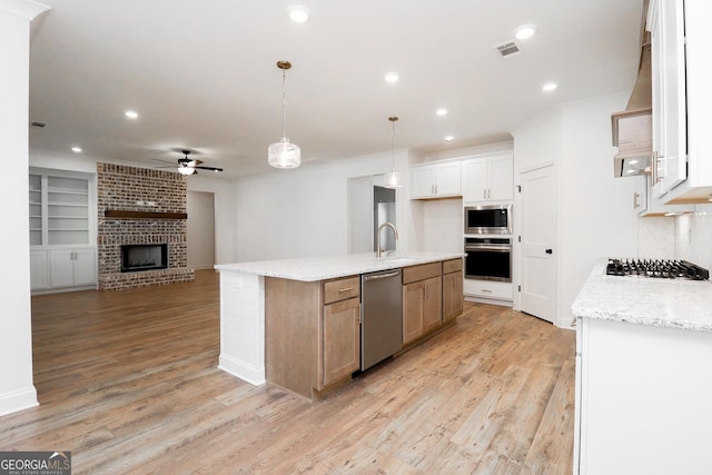 kitchen with open floor plan, recessed lighting, appliances with stainless steel finishes, light wood-style floors, and a sink