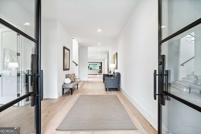 hall with french doors and light hardwood / wood-style flooring