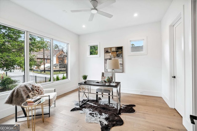 home office with light wood-type flooring and ceiling fan