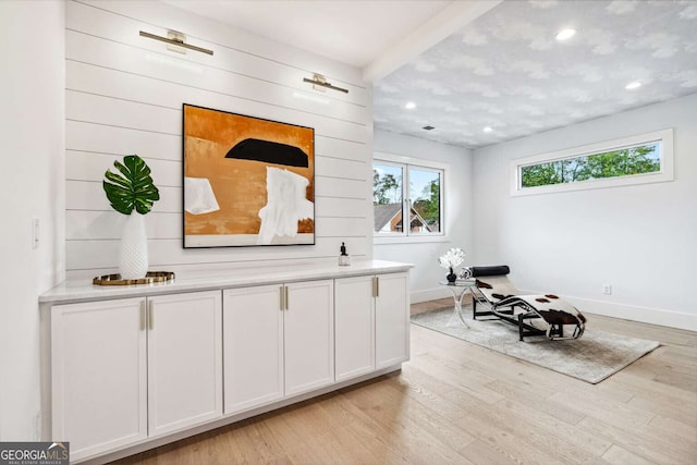 sitting room featuring beam ceiling and light hardwood / wood-style floors