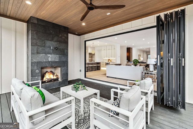 interior space with an outdoor living space with a fireplace and ceiling fan