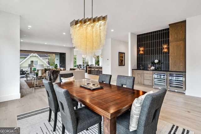 dining space with light hardwood / wood-style floors, wine cooler, and an inviting chandelier