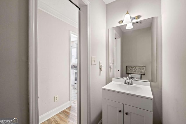 bathroom with vanity, ornamental molding, and wood-type flooring